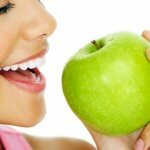 Женщина кушает зеленое яблоко
